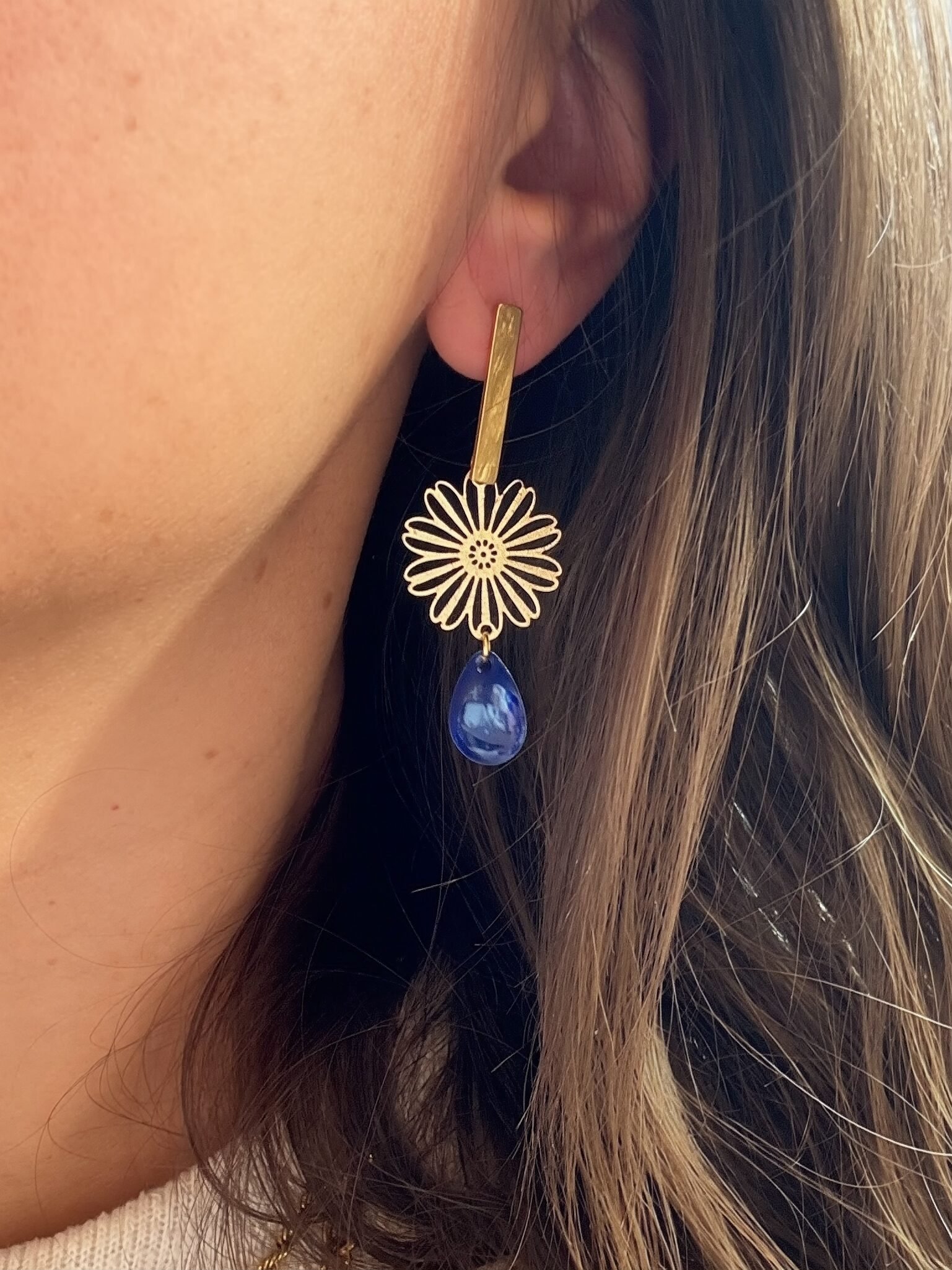 Boucle d’oreille AMANDA bleue avec fleur dorée et goutte bleue marbrée portée à l’oreille